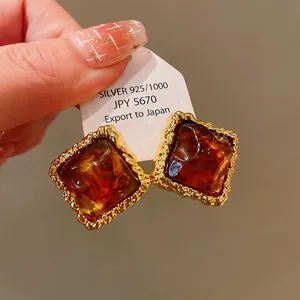 Detailed close-up of vintage amber-style square earrings with textured gold frames