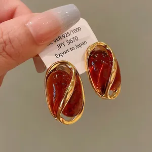Close-up detail of vintage gold-framed earrings with polished reddish-brown teardrop stones