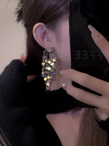Detailed close-up showing shimmering silver sequin fringe drop earrings on a model