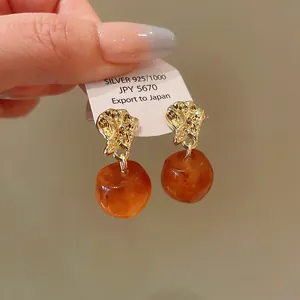Macro view of vintage gold-tone earrings featuring translucent amber drops and S925 post.