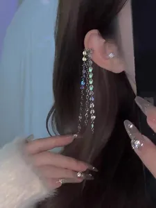 Detailed close-up showing a sparkling sequin tassel ear cuff with long silver chains on a model
