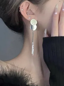 Macro view of elegant silver tassel earrings featuring textured disc sequins on a model