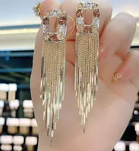 Macro view of gold tassel earrings with multicolored rhinestone rectangular studs