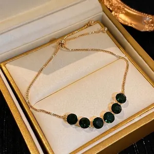 Elegant adjustable gold slider bracelet with six green gemstones in a luxury gift box