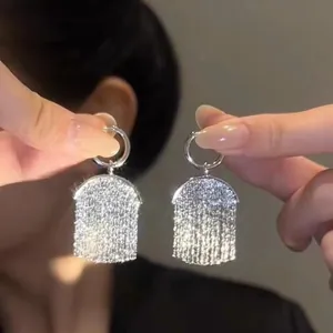 Macro view of silver-toned sequin tassel earrings with sparkling designer aesthetic
