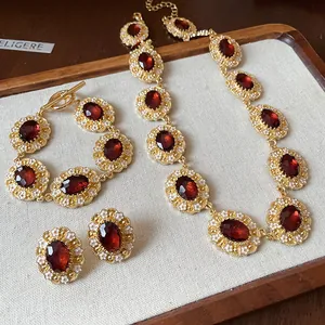 Macro detail of a vintage jewelry set featuring red stones and enamel flowers