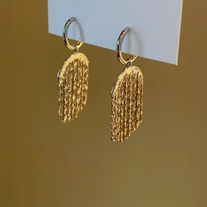 Close-up view showing the intricate texture of gold sequin tassel earrings hanging.
