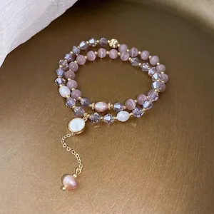 Close-up of double-strand bracelet with pink beads and dangling pearl charm