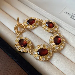 Close-up of vintage court-style bracelet with red gems and white enamel floral detail