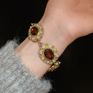 Close-up of vintage court style bracelet with amber-colored oval stones and white flowers