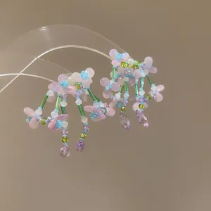 Detalle de los pendientes hechos a mano con flores de cuentas de colores y aguja de plata