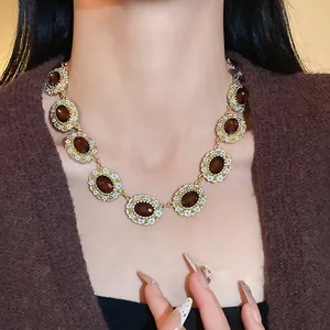 Close-up of a vintage enamel flower necklace with oval brown stones on a model