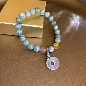 Detail shot of green jade bead bracelet with purple donut pendant and gold accents.