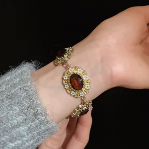 Close-up of vintage court style bracelet with amber stones and white enamel flowers.