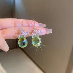 Close-up of elegant green teardrop earrings with delicate pink zircon flower details.