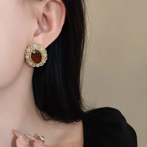 Close-up of vintage palace style earrings with white enamel flowers and red gemstone