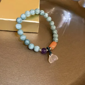 Detailed view of a multi-colored beaded bracelet with a translucent lotus pendant