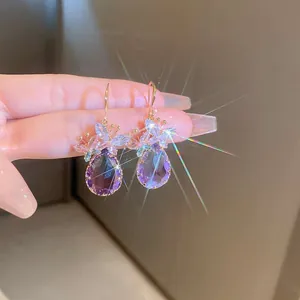 Detailed view of purple teardrop earrings with zircon flower motifs and gold hooks.