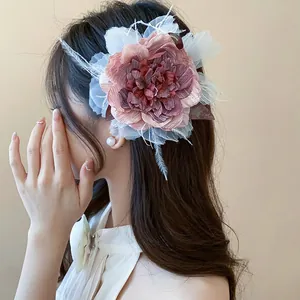 Detailansicht einer eleganten rosa Stoffblumen-Haarspange mit Federn bei einer Frau