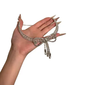 Französische Halskette mit Schleife, Strass, Quasten und Perlen auf weißem Grund.