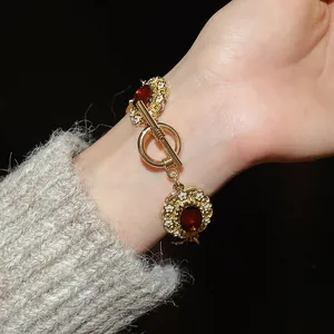 Detailed view of vintage gold bracelet with red oval gems and white flower enamel