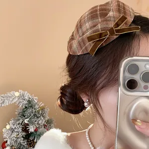 Detailansicht einer braunen karierten Baskenmützen-Haarklammer mit Samtschleife an einem Model