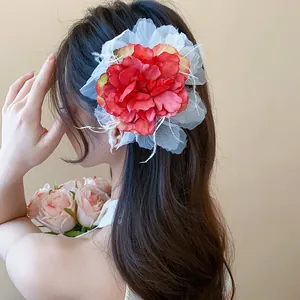 Eleganter rot-weißer Stoffblumen-Haarclip an langem welligem Haar für süßen Look