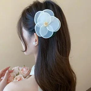 Detailansicht eines eleganten Haarclips mit weißer Stoffblume an gewelltem braunem Haar
