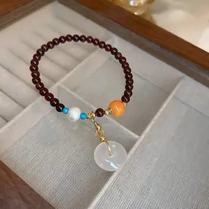 Elegant beaded bracelet with red quartz pearls and a white pi disc pendant.