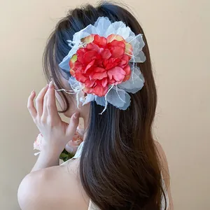 Detaillierte Nahaufnahme einer großen rot-weißen Stoffblumen-Haarklammer in gewelltem Haar.