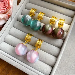 Three pairs of elegant resin ball dangle earrings in a grey jewelry display case