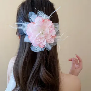 Detailansicht einer großen rosa Stoffblumen-Haarspange mit weißen Federn im Haar.
