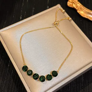 Detailed macro view of elegant gold adjustable bracelet featuring six dark green round crystals