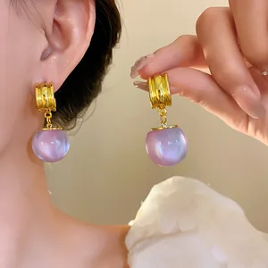 Close-up of lavender resin geometric pendant earrings on model with gold-tone accents.