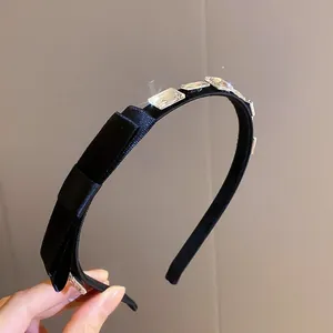Dettaglio del cerchietto in velluto nero con strass quadrati scintillanti e fiocco