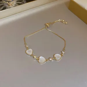 Detailed view of an adjustable gold heart bracelet with white stones and zircons.