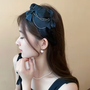 Elegante cerchietto in raso nero con fiocchi e catene di strass su una modella