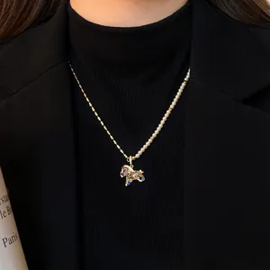 Détail d'un collier de perles avec pendentif cheval serti de zircons sur col roulé noir.