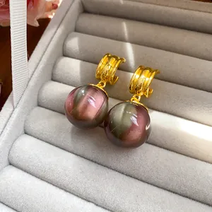 Detail view of stylish resin cat-eye drop earrings with gold-toned hoops in a jewelry box