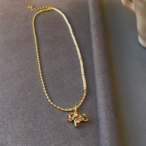Vue détaillée d'un collier pendentif cheval plaqué or avec zircons colorés et perles