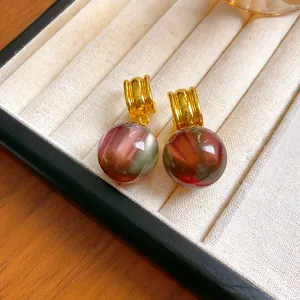 Detailed close-up view of elegant resin ball drop earrings featuring a marbled reddish-brown finish