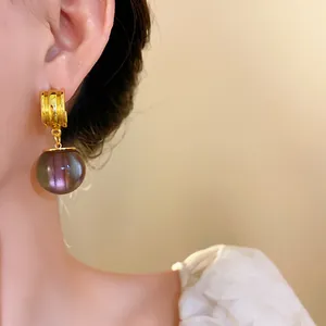 Close-up of elegant geometric resin drop earrings with a purple gradient effect and gold base