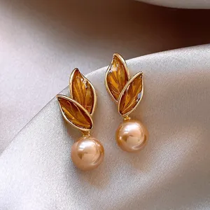 Detailed view of French-style gold earrings featuring amber leaves and champagne pearls.