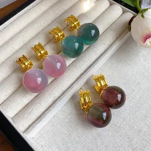 Close-up detail of elegant irregular resin geometric stud earrings resting in a beige jewelry box