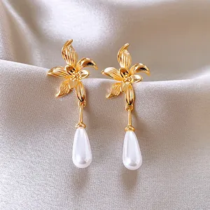 Elegant French vintage gold flower earrings with teardrop pearl dangles on silk background