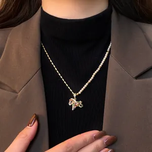 Élégant collier avec pendentif cheval en perles et zircons, porté sur un blazer.