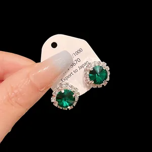Elegant emerald green zircon stud earrings with sparkling halo detail on white card