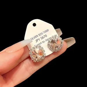 Macro view of elegant silver cubic zirconia halo stud earrings presented on a white card