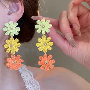 Close-up of vibrant triple-layered floral drop earrings in woven chiffon texture