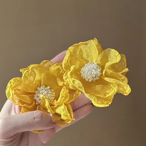 Detail of yellow chiffon flower earrings with white pearl bead centers for beach style.